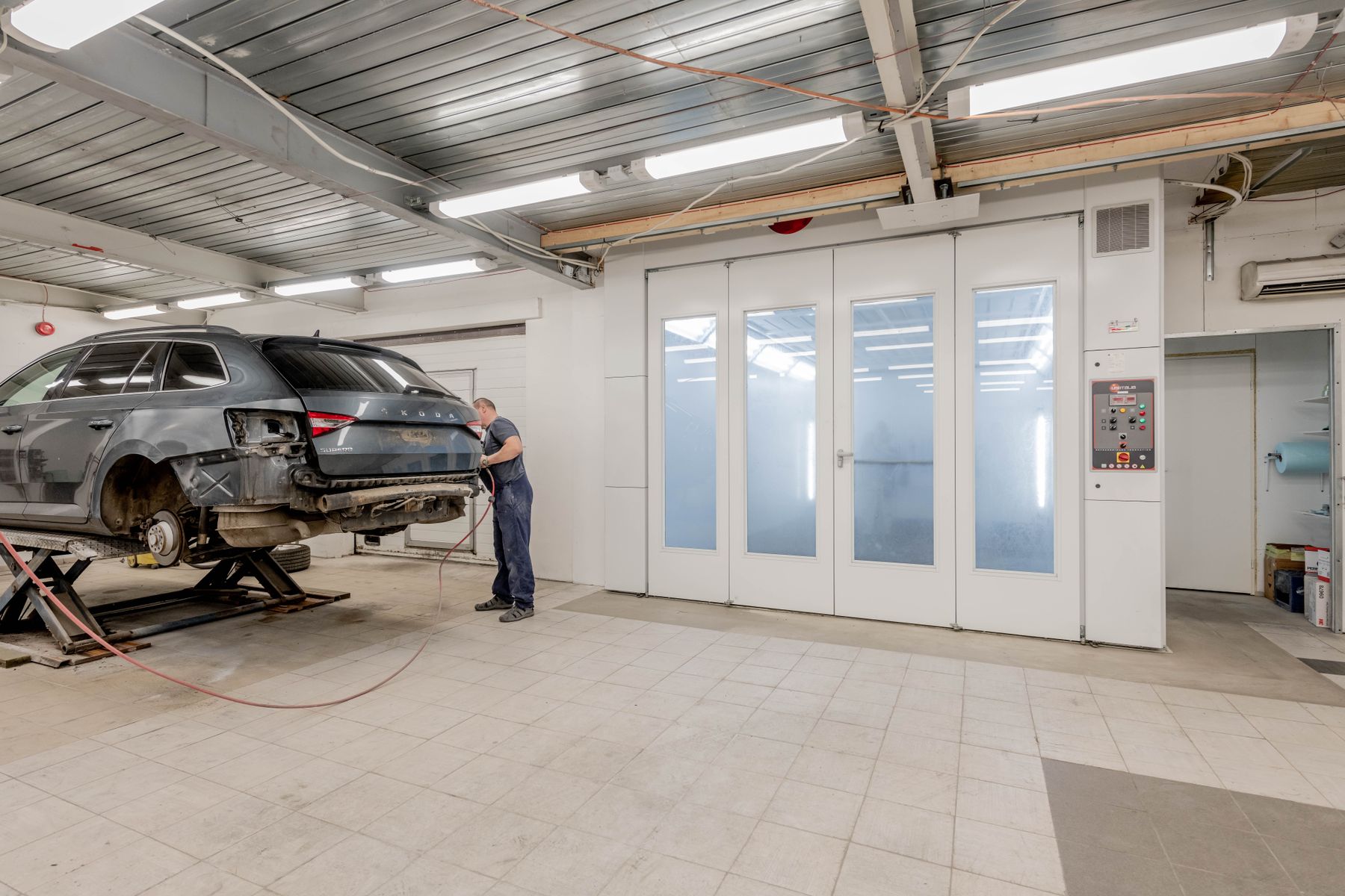 A mechanic works on a vehicle in a bright repair workshop.